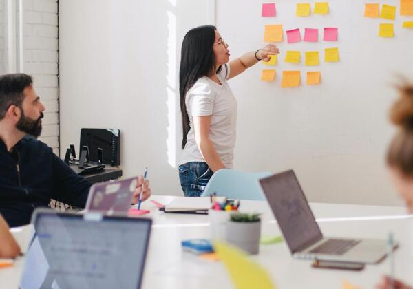 Woman giving presentation using sticky notes on a whiteboard