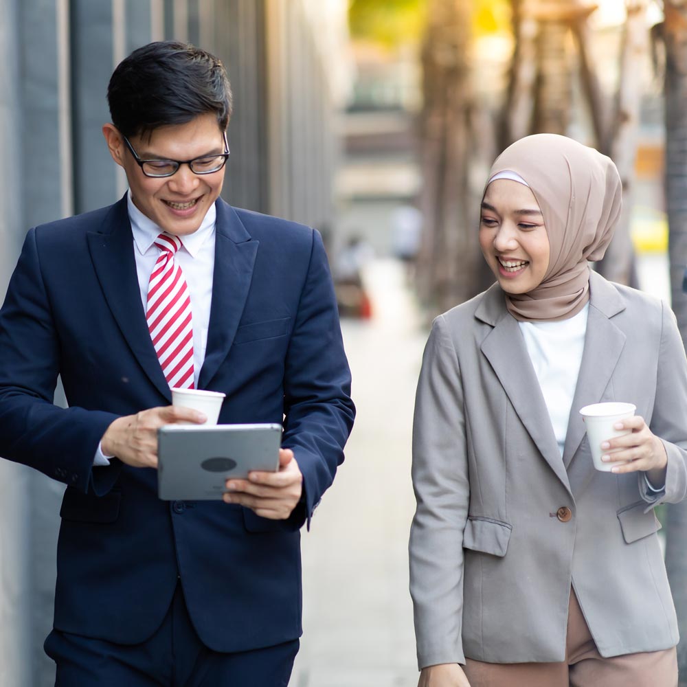 Business collegues looking at tablet while walking